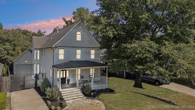 view of front of house with a porch, a garage, a yard, and an outbuilding