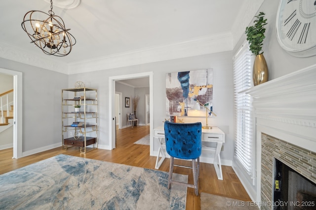 interior space with wood finished floors, baseboards, ornamental molding, a tile fireplace, and a chandelier