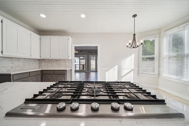 room details with decorative light fixtures, tasteful backsplash, stainless steel gas stovetop, and white cabinetry