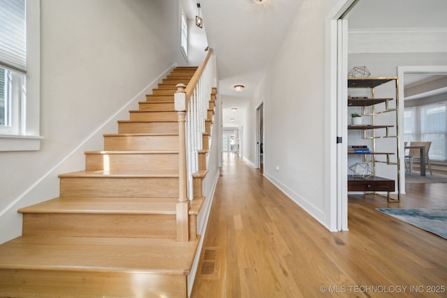 stairway with plenty of natural light, visible vents, and wood finished floors