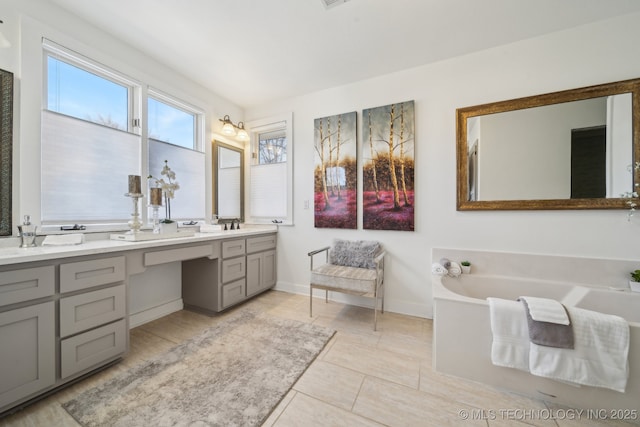 full bathroom with double vanity, visible vents, baseboards, and a garden tub