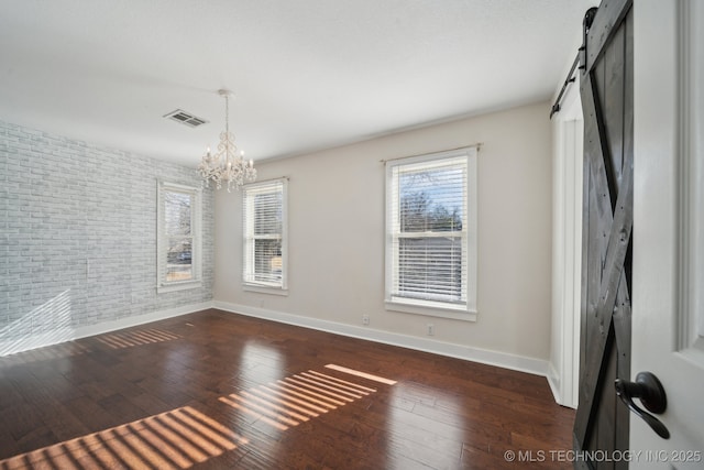 unfurnished room featuring hardwood / wood-style flooring, a barn door, visible vents, and a chandelier