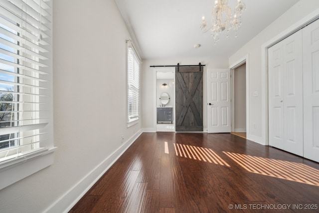 entrance foyer featuring a barn door, baseboards, a chandelier, and hardwood / wood-style flooring