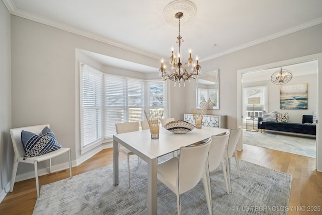 dining room with crown molding, baseboards, light wood-type flooring, and an inviting chandelier