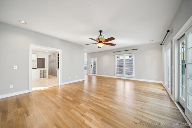 empty room featuring light wood-type flooring, a wealth of natural light, and ceiling fan