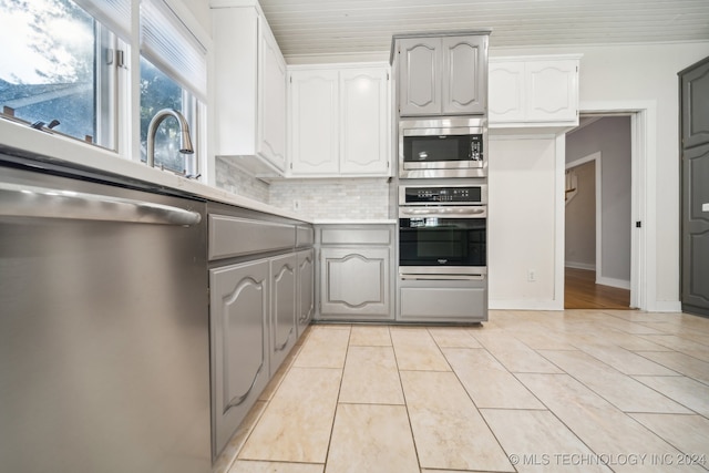 kitchen featuring sink, stainless steel appliances, tasteful backsplash, white cabinets, and light tile patterned flooring