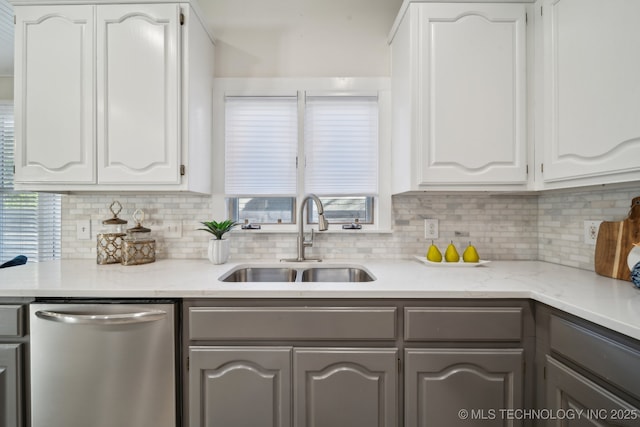 kitchen featuring stainless steel dishwasher, decorative backsplash, gray cabinets, and a sink