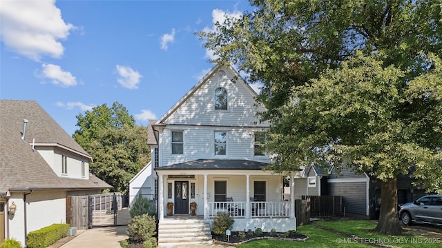 view of front of home featuring a porch, a gate, fence, and a front yard