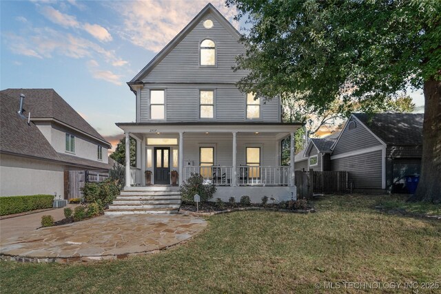 view of front of home featuring covered porch, a front yard, and fence