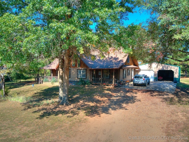 log home with covered porch, a front yard, an outbuilding, and a garage