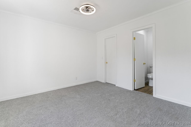 unfurnished bedroom with connected bathroom, dark colored carpet, and crown molding