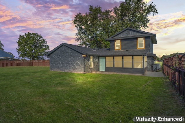 back house at dusk featuring a lawn