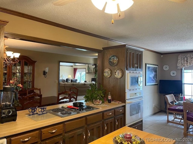 kitchen with white appliances, dark brown cabinets, ornamental molding, a textured ceiling, and light tile patterned flooring