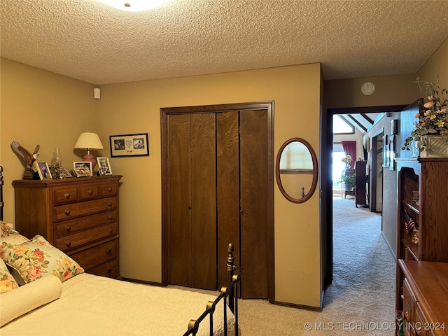 bedroom featuring light colored carpet, a closet, and a textured ceiling