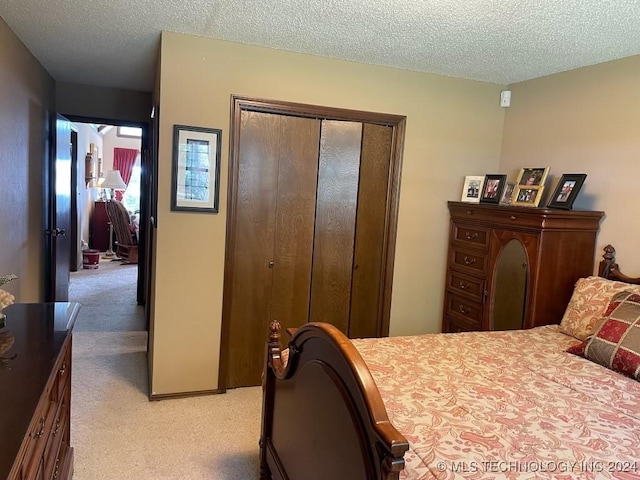 bedroom featuring light carpet, a closet, and a textured ceiling