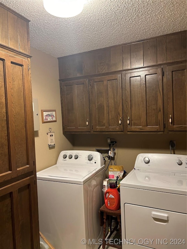 laundry area with washer and clothes dryer, cabinets, and a textured ceiling