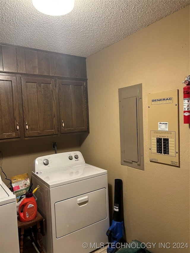 washroom featuring a textured ceiling, electric panel, cabinets, and washing machine and clothes dryer