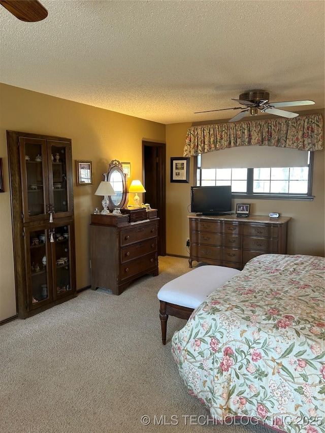 bedroom featuring light carpet, a textured ceiling, and ceiling fan