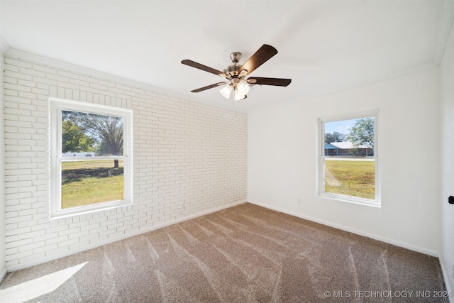 spare room with a wealth of natural light, carpet flooring, ceiling fan, and brick wall