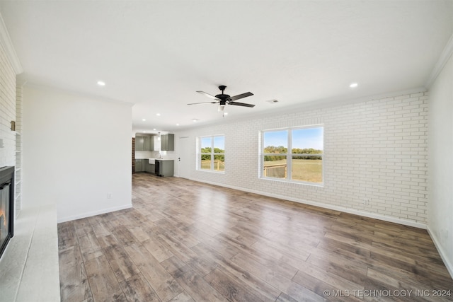 18440 County Road 3564, Ada, OK 74820 - unfurnished living room featuring brick wall, a large fireplace, a ceiling fan, wood finished floors, and crown molding