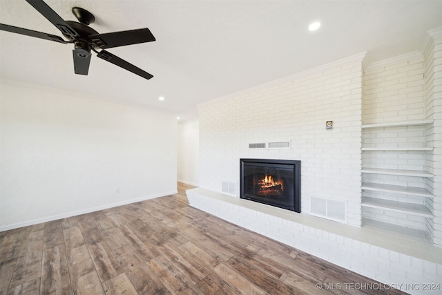 unfurnished living room with a fireplace, ornamental molding, ceiling fan, and hardwood / wood-style flooring