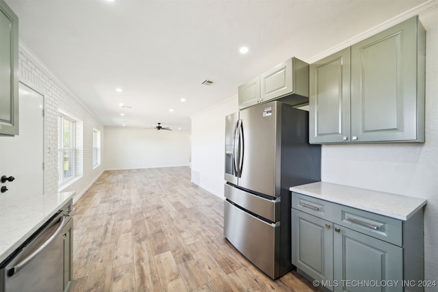 kitchen with light wood-type flooring, stainless steel appliances, ornamental molding, ceiling fan, and light stone countertops