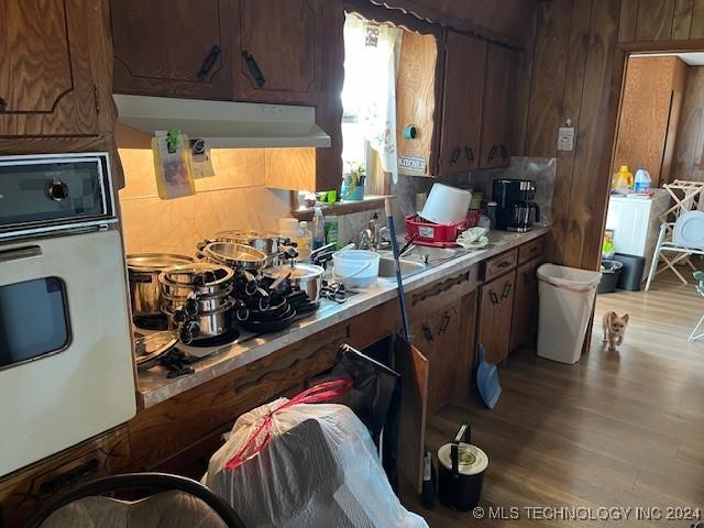 1384 Academy Rd, Bennington, OK 74723 - kitchen featuring oven, light countertops, wood finished floors, under cabinet range hood, and wooden walls