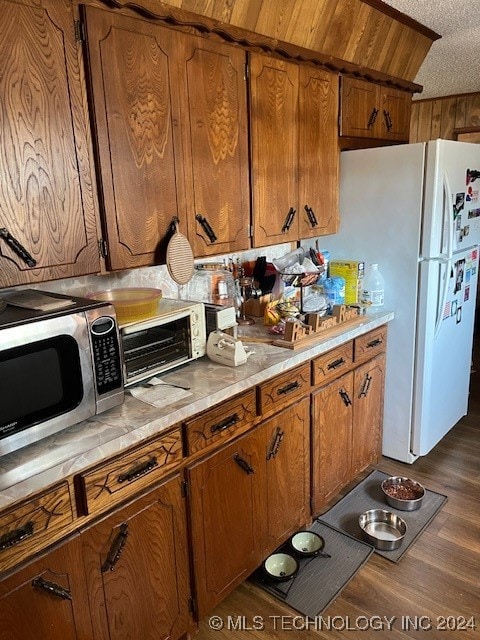 kitchen with a textured ceiling, white fridge, and dark hardwood / wood-style flooring