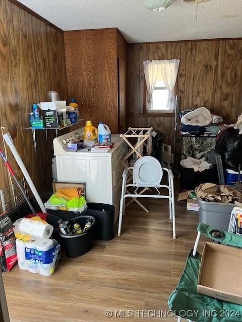 1384 Academy Rd, Bennington, OK 74723 - washroom featuring wood walls, washing machine and clothes dryer, wood finished floors, and a textured ceiling