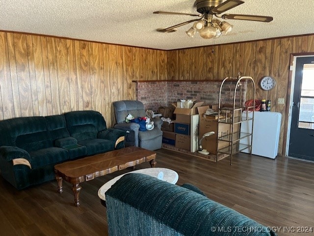 living room featuring wood walls, a textured ceiling, dark wood-type flooring, and ceiling fan