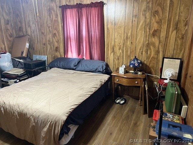 bedroom with wood walls and wood-type flooring