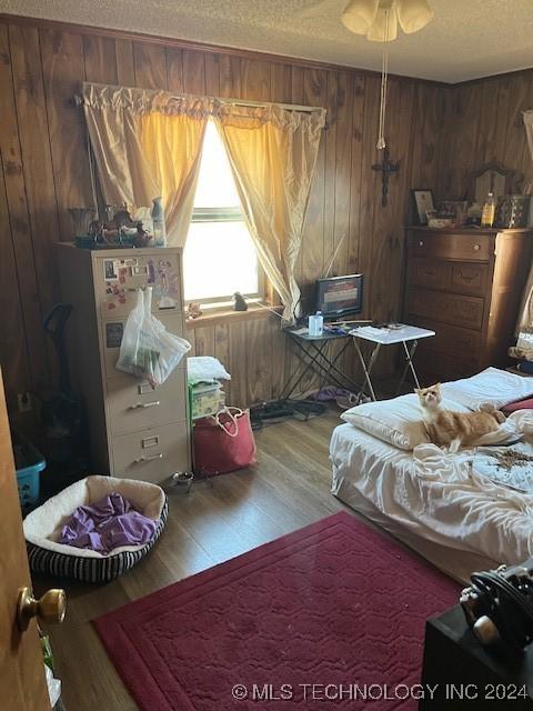 1384 Academy Rd, Bennington, OK 74723 - bedroom featuring wood finished floors, wood walls, and a textured ceiling