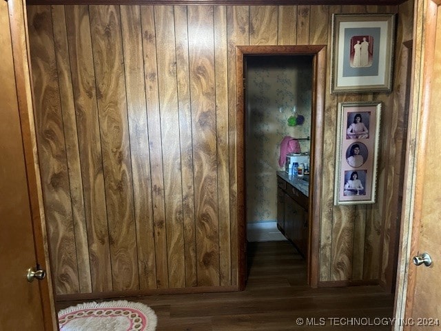 hall with wooden walls and dark wood-type flooring