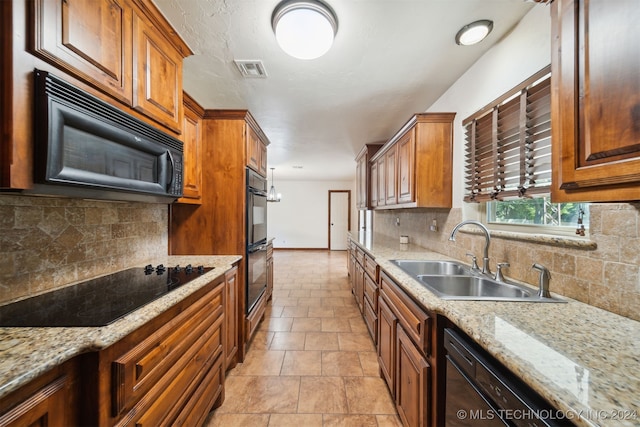 kitchen with a sink, black appliances, backsplash, and brown cabinets