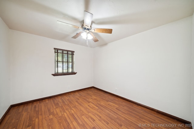 spare room featuring wood finished floors, baseboards, and a ceiling fan