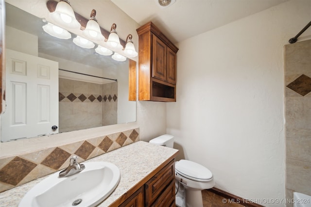 bathroom featuring tiled shower, vanity, and toilet