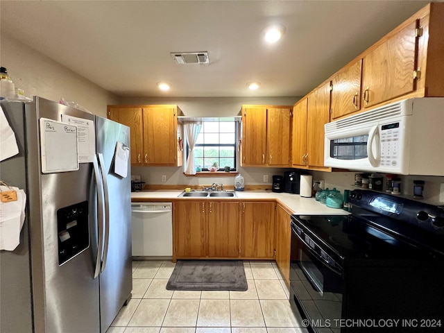 kitchen with white appliances, light tile patterned floors, and sink