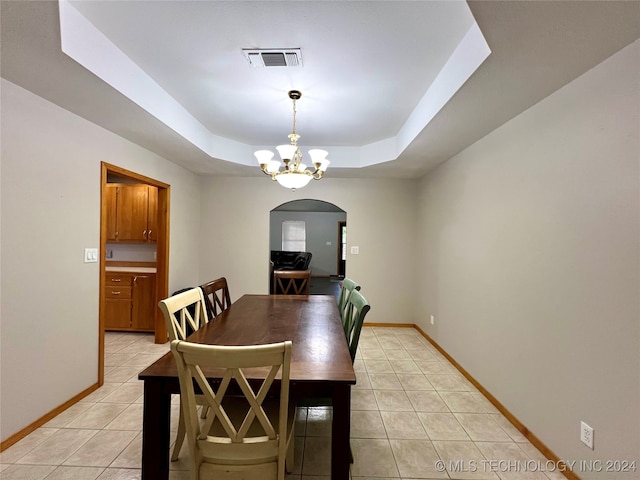 tiled dining space with a tray ceiling and a notable chandelier