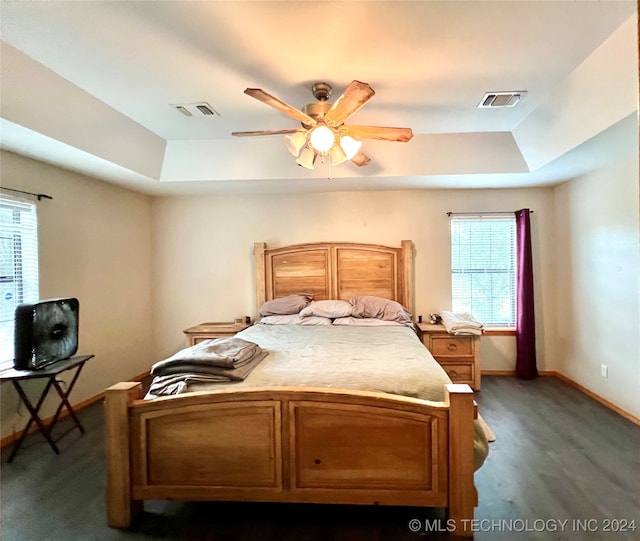 carpeted bedroom with ceiling fan and a raised ceiling