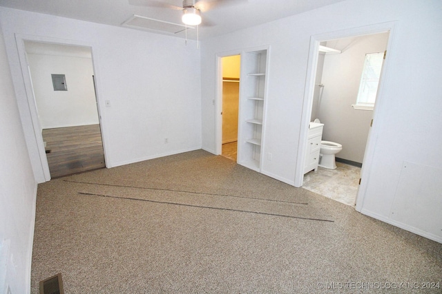 unfurnished bedroom with a walk in closet, ensuite bathroom, ceiling fan, and light carpet