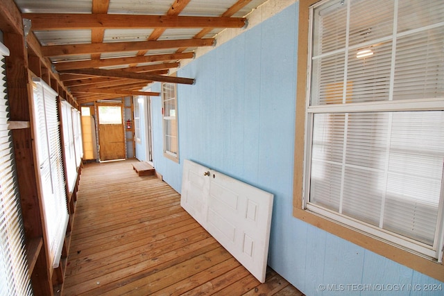 interior space with lofted ceiling with beams, light wood-type flooring, and wooden walls