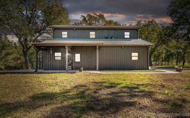 back house at dusk with a yard and a porch