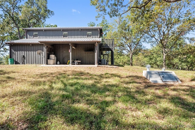 rear view of property featuring cooling unit and a lawn