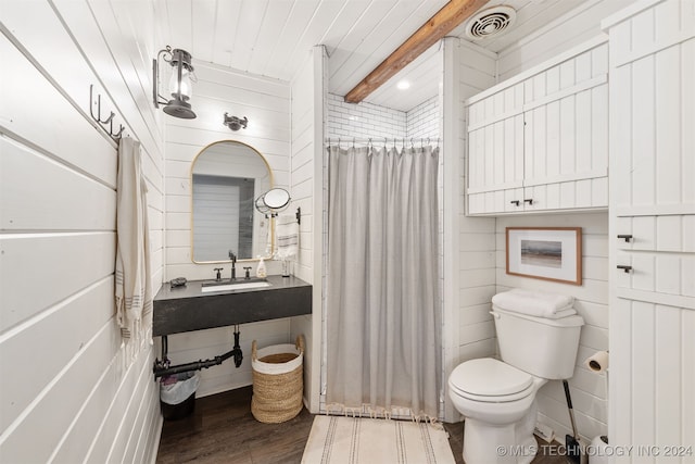 bathroom with sink, curtained shower, wood-type flooring, wooden walls, and toilet