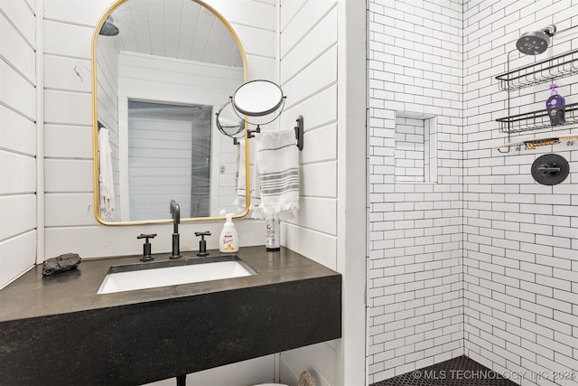 bathroom with vanity, wooden walls, and tiled shower