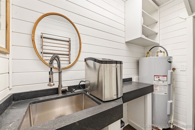 interior space with water heater, wood walls, and sink