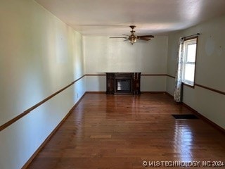 unfurnished room featuring ceiling fan, a fireplace, and dark hardwood / wood-style floors