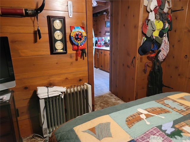 bedroom featuring wood walls and radiator heating unit