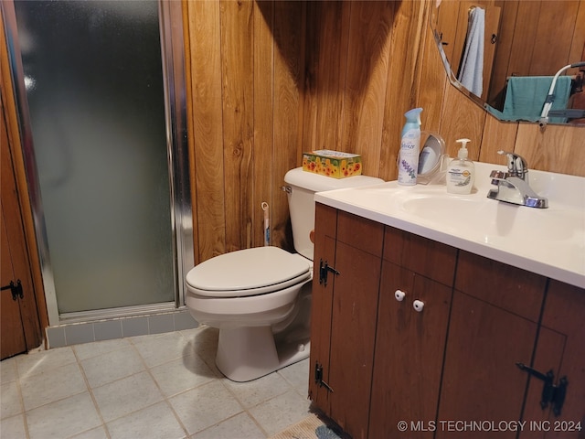 bathroom with vanity, wood walls, tile patterned floors, toilet, and a shower with door