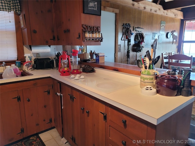 kitchen featuring white cooktop, kitchen peninsula, light tile patterned floors, and sink